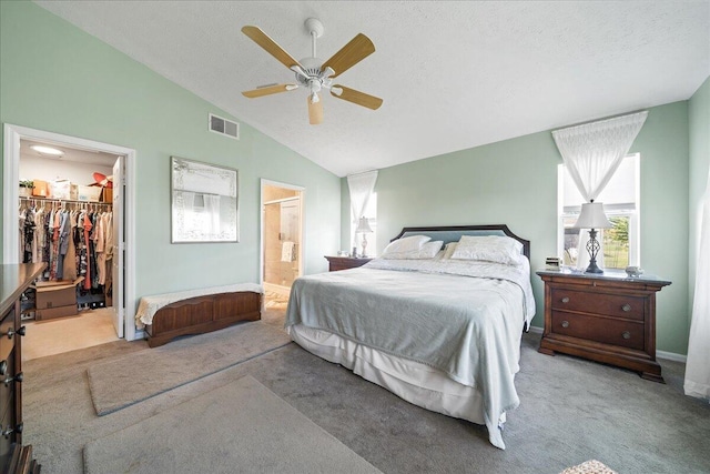 carpeted bedroom with ensuite bath, ceiling fan, vaulted ceiling, a walk in closet, and a closet