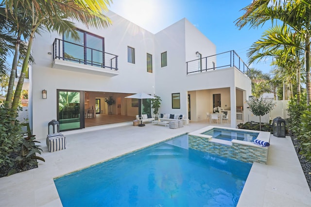 back of property featuring outdoor lounge area, a balcony, and stucco siding