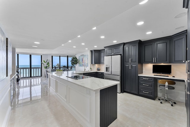 kitchen with stainless steel fridge, dark cabinetry, a sink, and built in study area