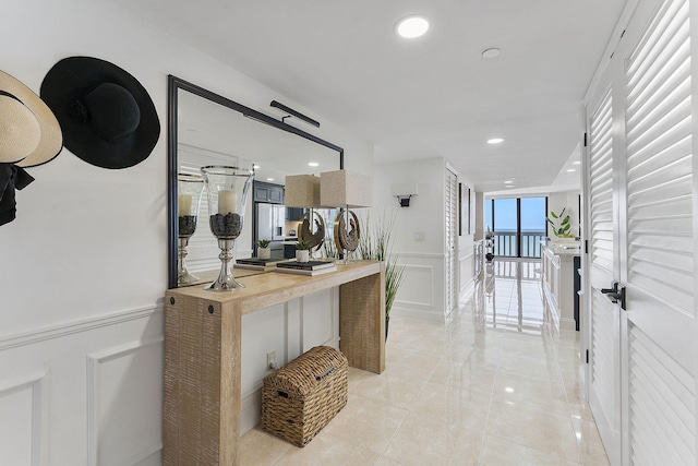 corridor featuring a wainscoted wall, a decorative wall, and recessed lighting