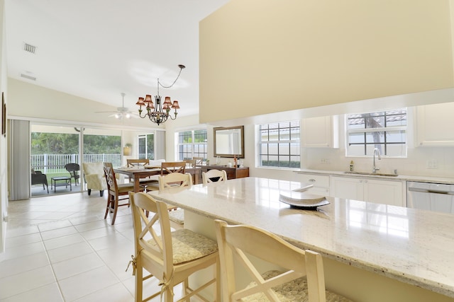 kitchen with sink, light stone counters, dishwasher, pendant lighting, and white cabinets