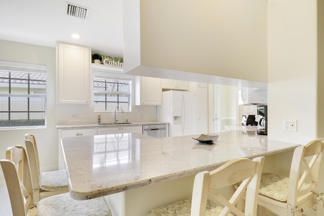 kitchen with white cabinetry, sink, a kitchen breakfast bar, and a healthy amount of sunlight