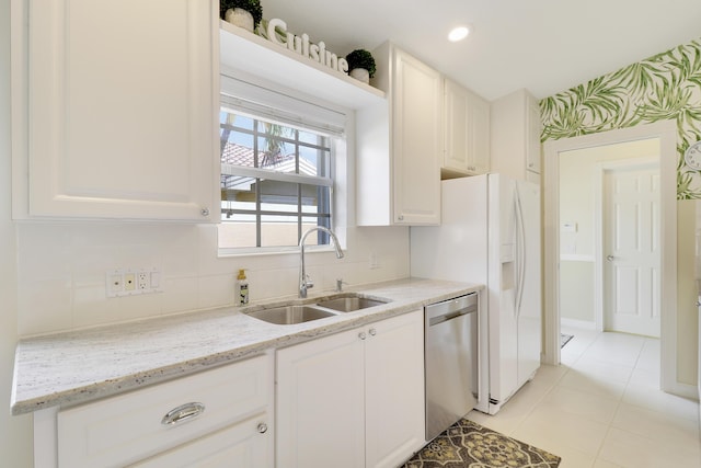 kitchen with sink, white cabinetry, tasteful backsplash, dishwasher, and light stone countertops