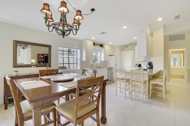 dining room with sink, light tile patterned floors, and a chandelier