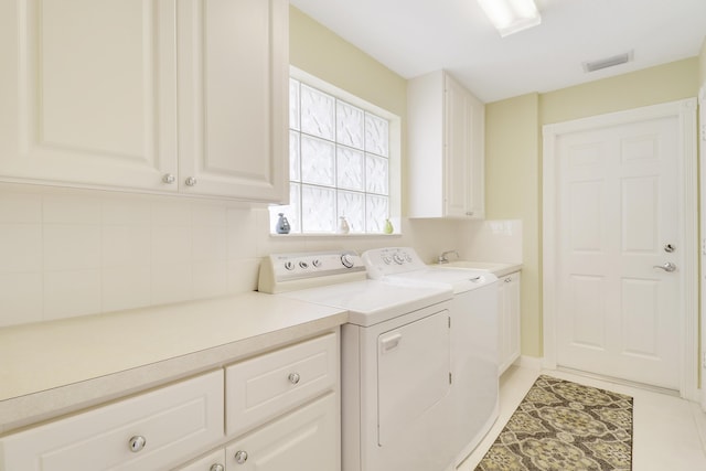 washroom with independent washer and dryer, cabinets, and light tile patterned floors