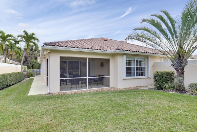 back of house with a lawn, a sunroom, and a patio area