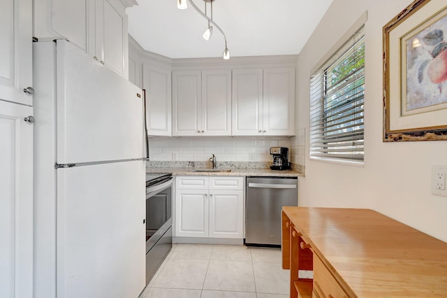 kitchen featuring sink, stainless steel appliances, white cabinets, light tile patterned flooring, and decorative backsplash