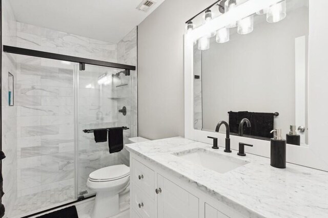 bathroom with vanity, a shower with door, and toilet