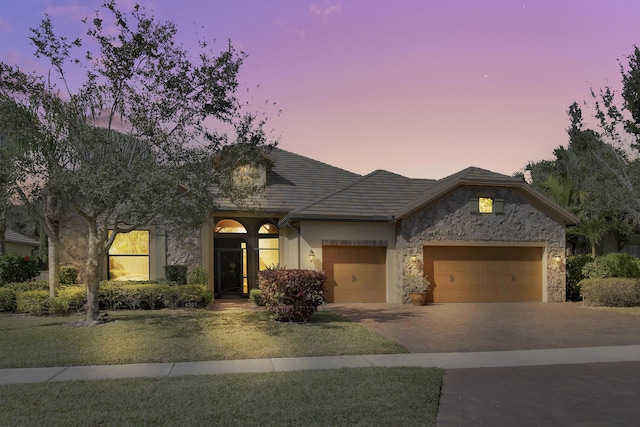 view of front of home with a garage and a lawn