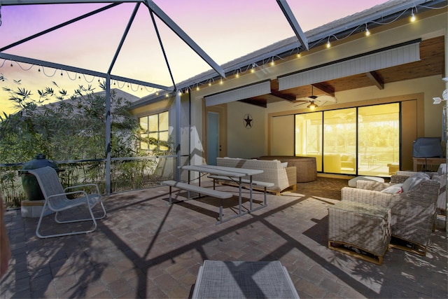 patio terrace at dusk with outdoor lounge area, ceiling fan, and a lanai