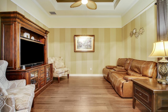 living room featuring crown molding, a tray ceiling, ceiling fan, and light hardwood / wood-style flooring