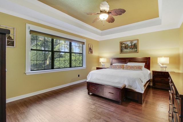 bedroom featuring crown molding, dark hardwood / wood-style floors, and a tray ceiling