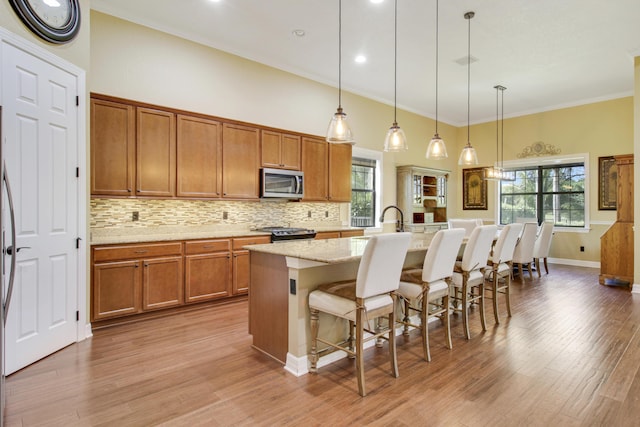 kitchen with hanging light fixtures, decorative backsplash, a breakfast bar area, and a center island with sink