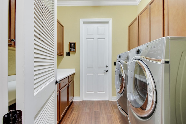 laundry area with crown molding, light hardwood / wood-style flooring, cabinets, and washing machine and clothes dryer