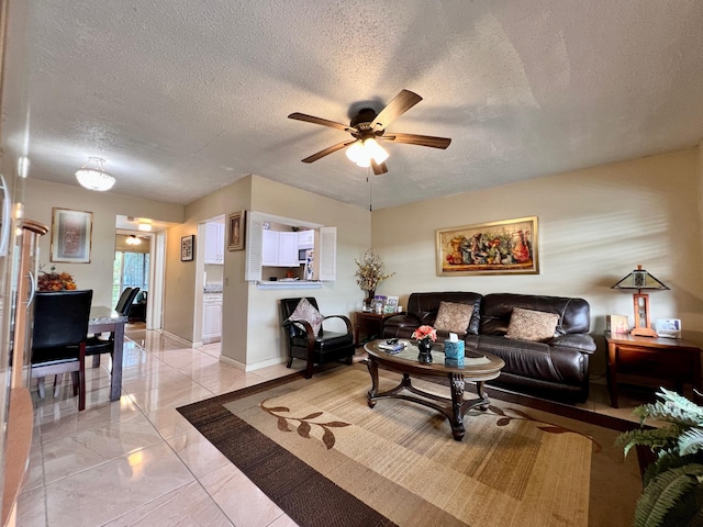 living room featuring ceiling fan and a textured ceiling