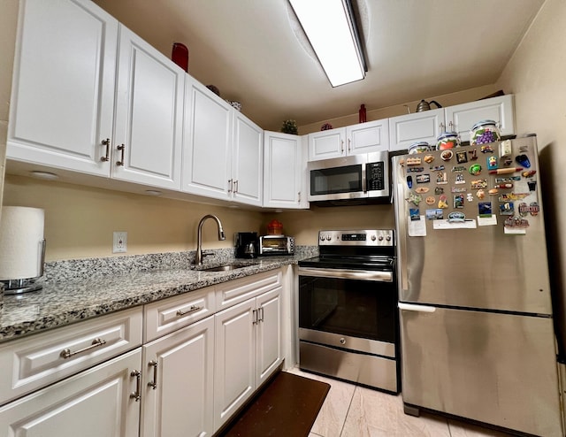 kitchen with light stone counters, stainless steel appliances, sink, and white cabinets