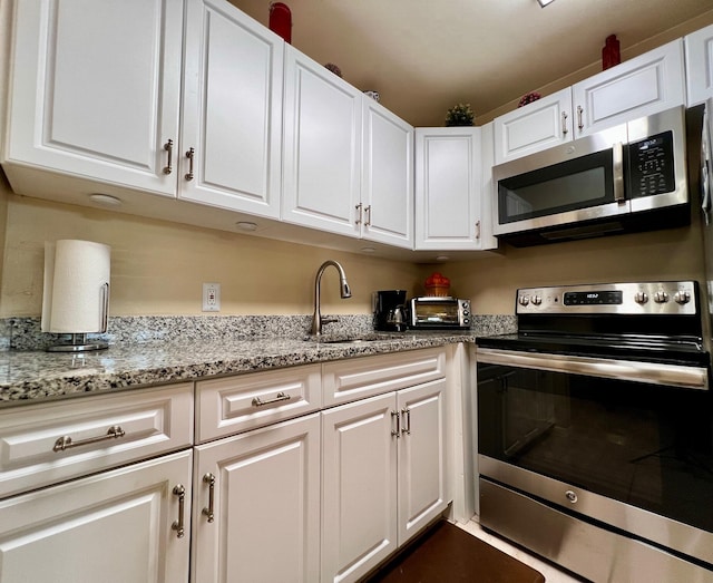 kitchen featuring white cabinetry, sink, light stone counters, and appliances with stainless steel finishes