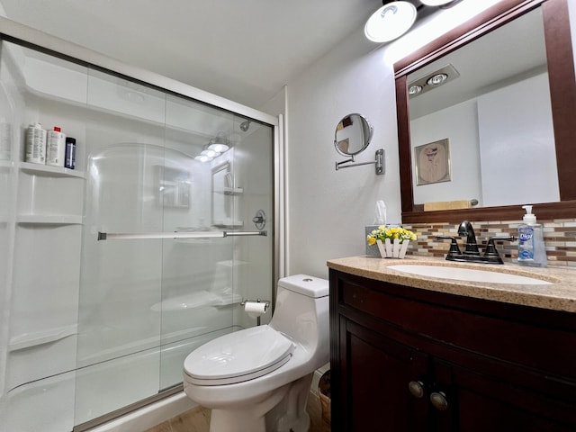 bathroom featuring an enclosed shower, vanity, decorative backsplash, and toilet