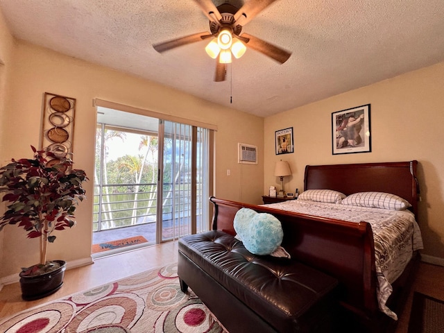 bedroom featuring access to exterior, a wall unit AC, a textured ceiling, and ceiling fan