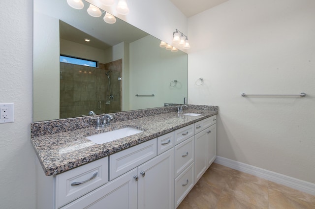 bathroom featuring a sink, a shower stall, baseboards, and double vanity