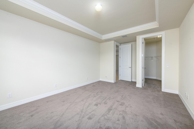 unfurnished bedroom featuring a tray ceiling, visible vents, ornamental molding, carpet flooring, and baseboards