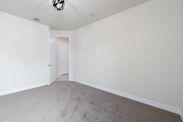 carpeted spare room with visible vents and baseboards