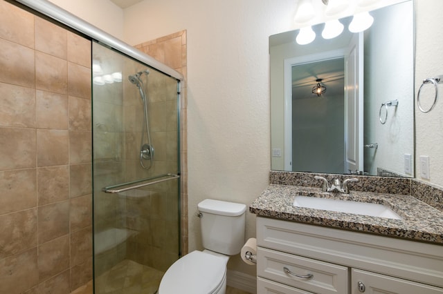 full bathroom with toilet, a shower stall, and vanity