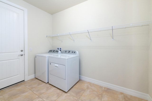 laundry room with laundry area, washer and clothes dryer, baseboards, and light tile patterned floors