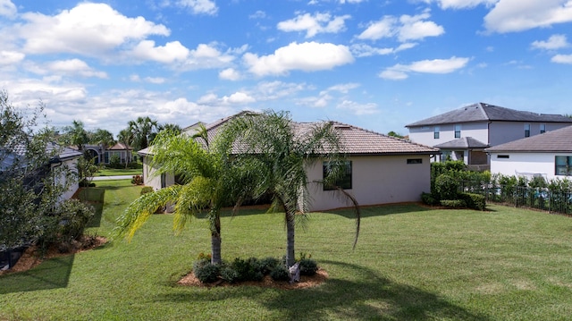 exterior space with a yard, fence, a tile roof, and stucco siding