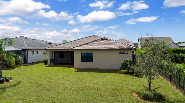 back of house featuring a tile roof, fence, a lawn, and stucco siding