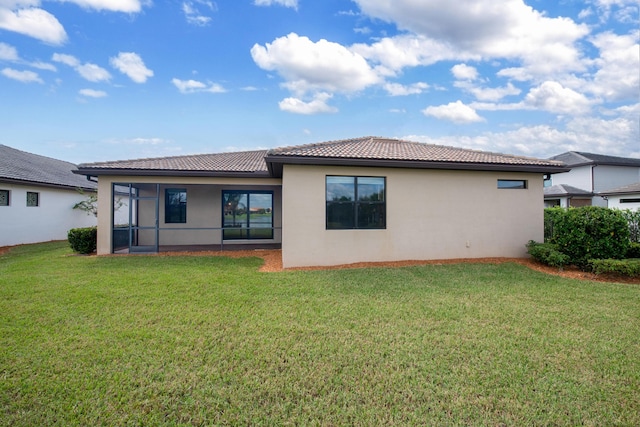 back of property featuring stucco siding, a tiled roof, a sunroom, and a yard