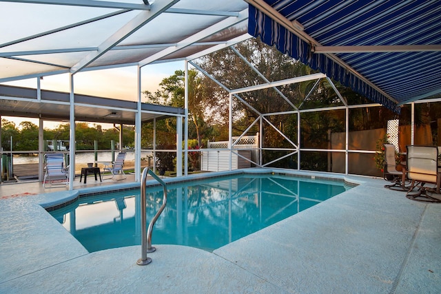 pool at dusk featuring a storage shed, a lanai, and a patio area