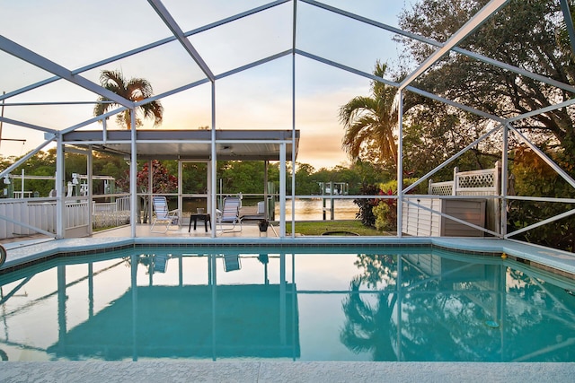 pool at dusk with a lanai and a patio area