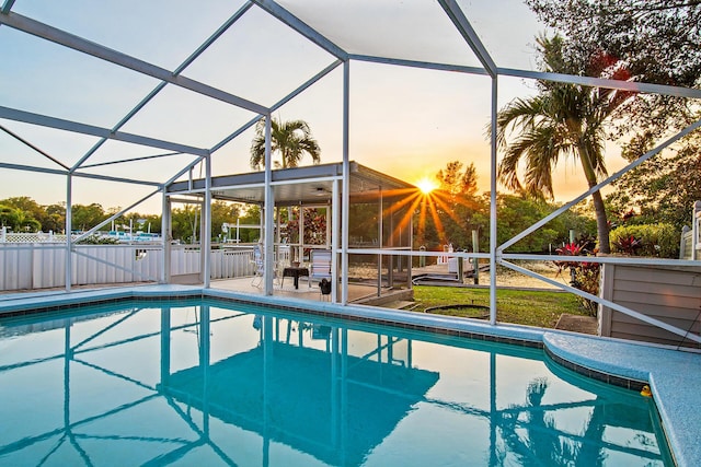 pool at dusk with a patio area and glass enclosure