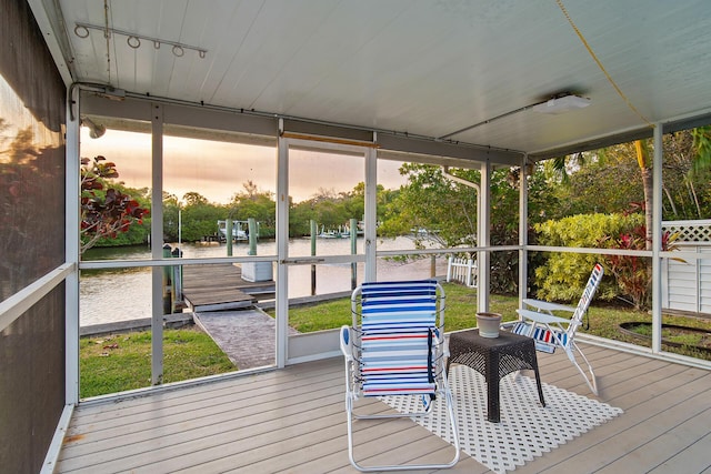 sunroom featuring track lighting and a water view