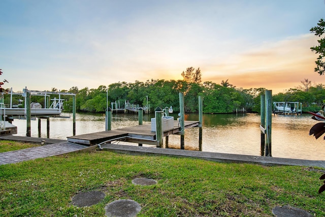 view of home's community featuring a water view, a dock, and a lawn