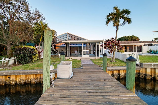 dock area featuring a water view, a lanai, and a lawn