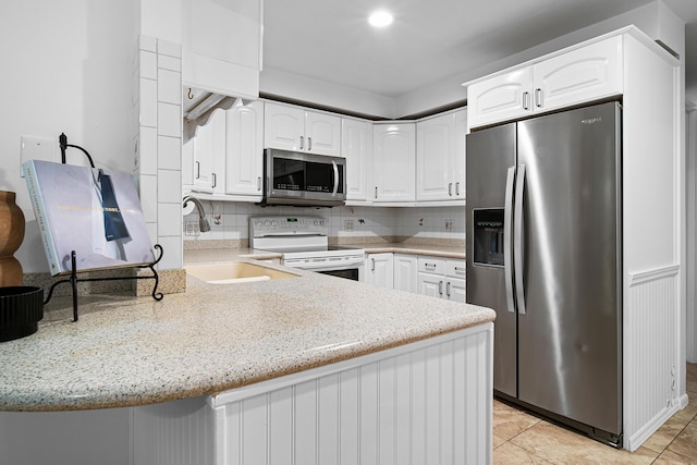 kitchen with stainless steel appliances, kitchen peninsula, and white cabinets