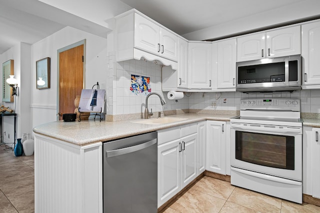 kitchen with appliances with stainless steel finishes, sink, white cabinets, and decorative backsplash