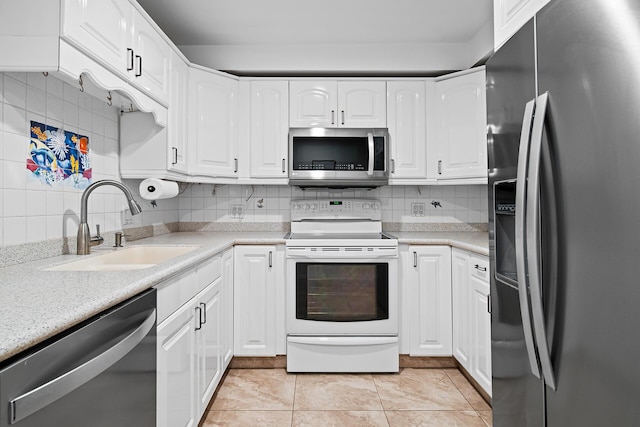 kitchen featuring sink, white cabinetry, light tile patterned floors, stainless steel appliances, and backsplash