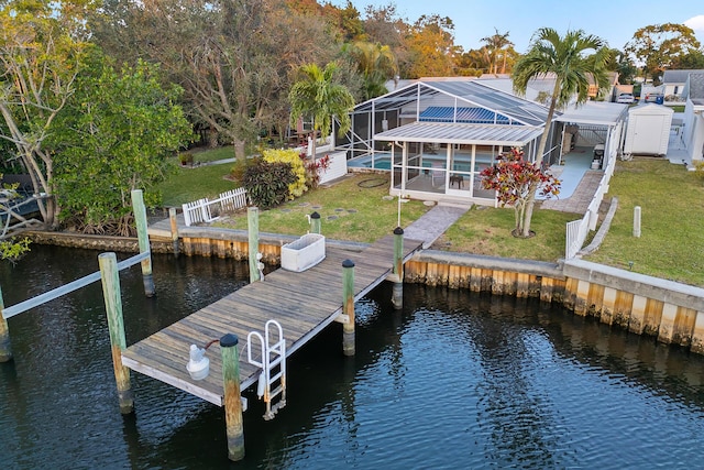 view of dock featuring a water view, a patio, a lanai, and a lawn