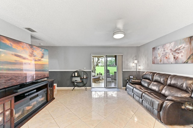 living room with visible vents, a ceiling fan, light tile patterned flooring, a textured ceiling, and baseboards