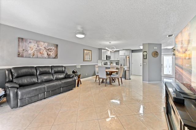 living area featuring light tile patterned floors, baseboards, visible vents, and a textured ceiling