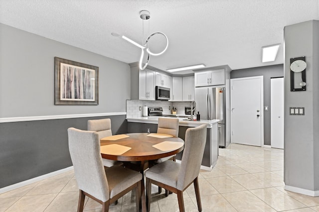 dining room featuring light tile patterned flooring, a textured ceiling, and baseboards