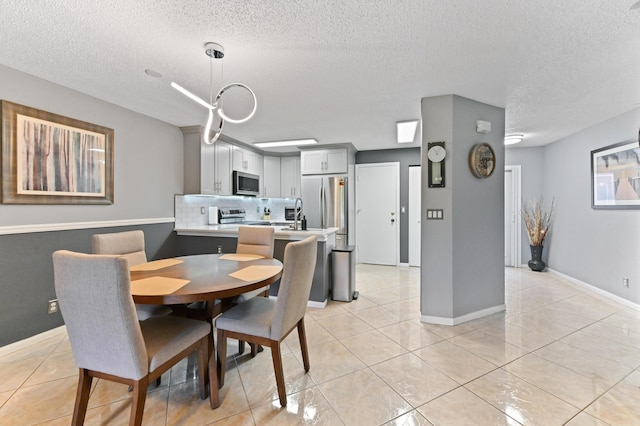 dining space with light tile patterned floors, baseboards, and a textured ceiling