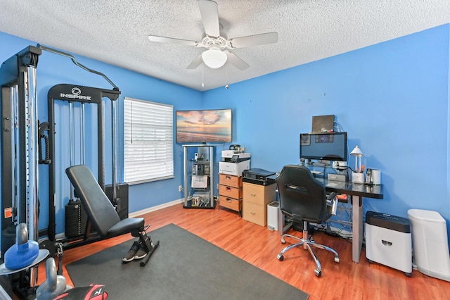 office space featuring ceiling fan, a textured ceiling, baseboards, and wood finished floors