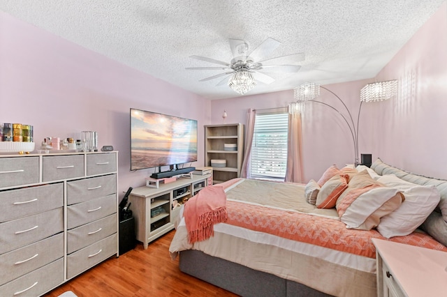 bedroom with a ceiling fan, light wood-style flooring, and a textured ceiling