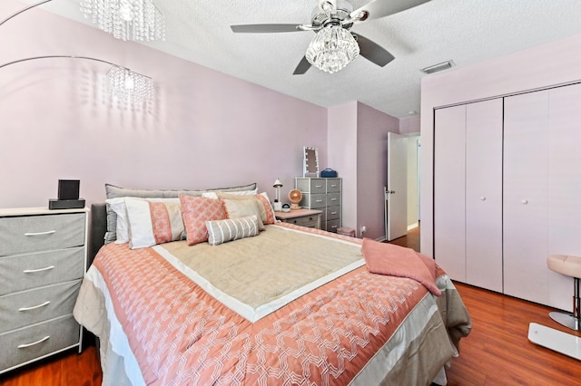 bedroom with visible vents, ceiling fan, wood finished floors, a textured ceiling, and a closet