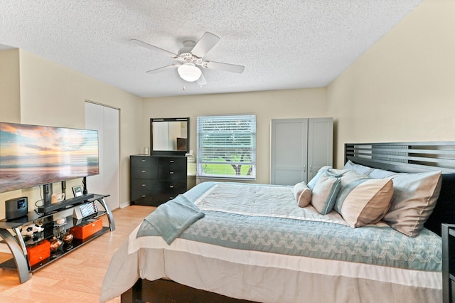 bedroom featuring light wood-style floors, a textured ceiling, and a ceiling fan