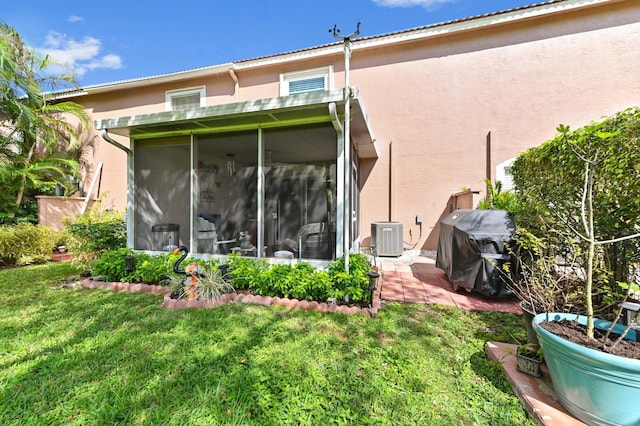 back of property featuring a yard, central AC unit, a sunroom, and stucco siding